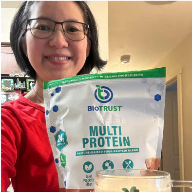 User generated content photo of smiling woman with glasses holding a bag of BioTRUST Low Carb Protein Powder