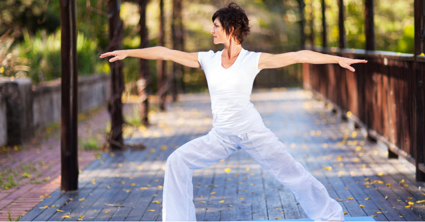 Photo of woman exercising with outstretched arms on a brick paver bridge